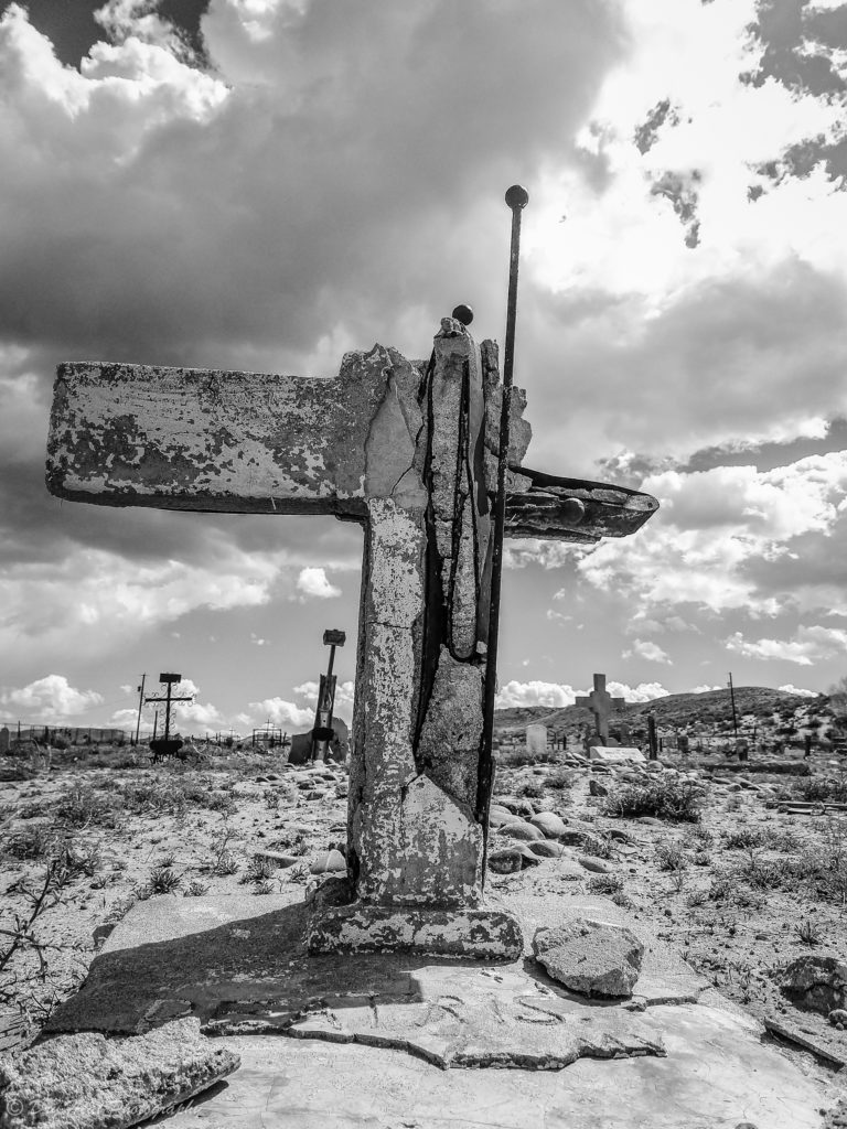 A broken concrete cross gravemarker at Our Lady of Guadalupe Cemetery in Peralta, New Mexico.