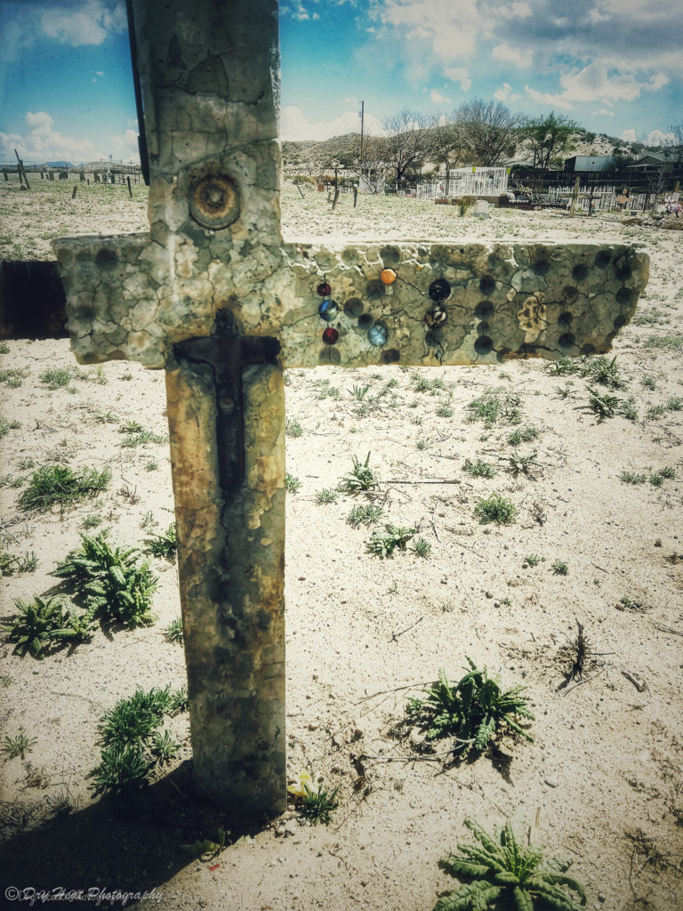 Glass marbles decorate this concrete cross grave marker at Our Lady of Guadalupe Cemetery in Peralta, New Mexico.