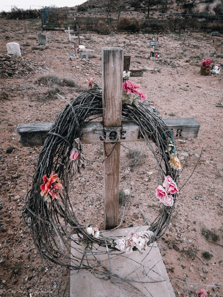 a wreath decorates this grave marker at Our Lady of Guadalupe Cemetery in Peralta, New Mexico.
